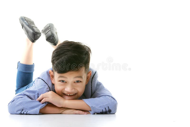 En 10-årig asiansk pojke i en tillfällig kavaj ligger på golvet och ler glatt i gott humör när man tittar på kameran.
