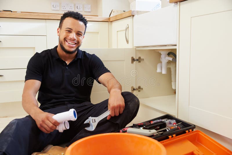 Encanador que senta-se em uma cozinha, retrato da raça misturada foto de stock Encanador que senta-se em uma cozinha, retrato da raça misturada foto de stock