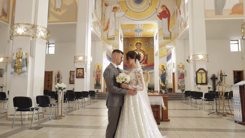 Encantadora familia recién casados pareja novia abrazando novio en una antigua ceremonia de boda de la iglesia matrimonio