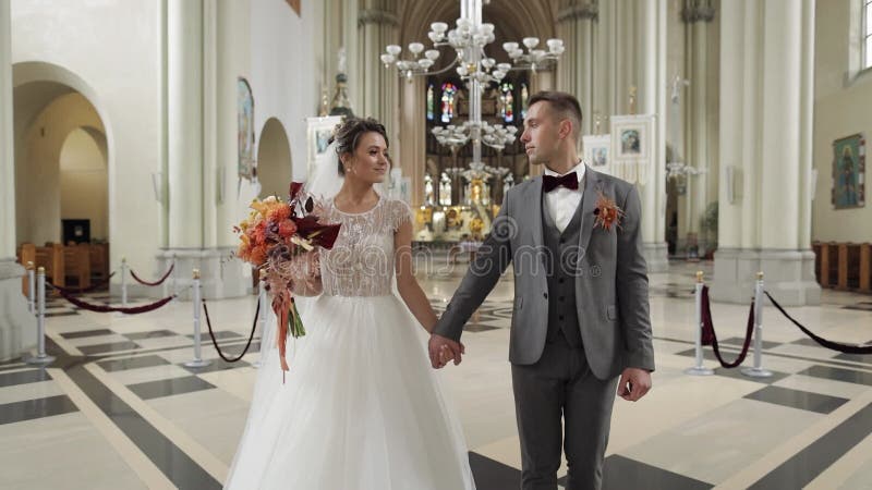 Encantadora familia recién casados pareja novia y novio caminando en una antigua ceremonia de boda de la iglesia matrimonio