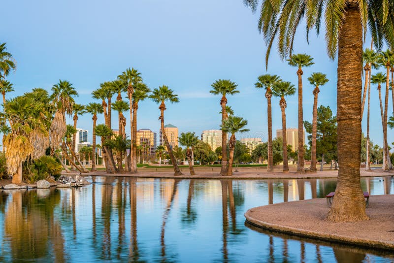 Office buildings in Phoenix, viewed from across the lagoon in Encanto Park, glow gold in the rays of the setting sun. Office buildings in Phoenix, viewed from across the lagoon in Encanto Park, glow gold in the rays of the setting sun.