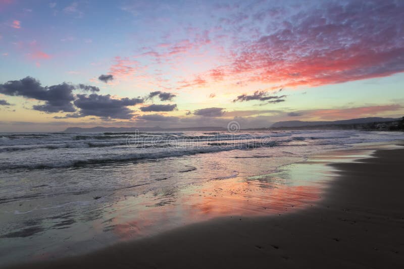Enchanting sunset. Storm sea with high waves. Unbelievable blue, pink, orange colors of the sky are reflected on the wet sand. royalty free stock images Enchanting sunset. Storm sea with high waves. Unbelievable blue, pink, orange colors of the sky are reflected on the wet sand. royalty free stock images