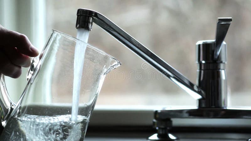 Enchendo um jarro com a água potável fresca