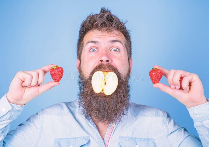 Enchimento do fruto A barba longa do moderno considerável do homem come a morango da posse da maçã O moderno surpreendido aprecia fotografia de stock royalty free Enchimento do fruto A barba longa do moderno considerável do homem come a morango da posse da maçã O moderno surpreendido aprecia fotografia de stock royalty free