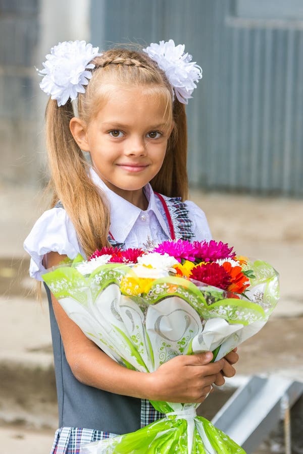 Encima del retrato de una colegiala de siete años con el ramo de flores fotografía de archivo Encima del retrato de una colegiala de siete años con el ramo de flores fotografía de archivo
