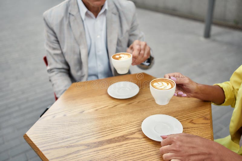 Encontro com um bom amigo Foto cortada de pessoas estilosas tomando café em um café ao ar livre fotografia de stock