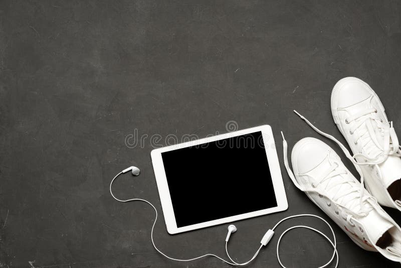 Endecha plana de las zapatillas de deporte blancas de la moda en fondo negro con el teléfono, auriculares, tableta, libro de la c fotografía de archivo Endecha plana de las zapatillas de deporte blancas de la moda en fondo negro con el teléfono, auriculares, tableta, libro de la c fotografía de archivo
