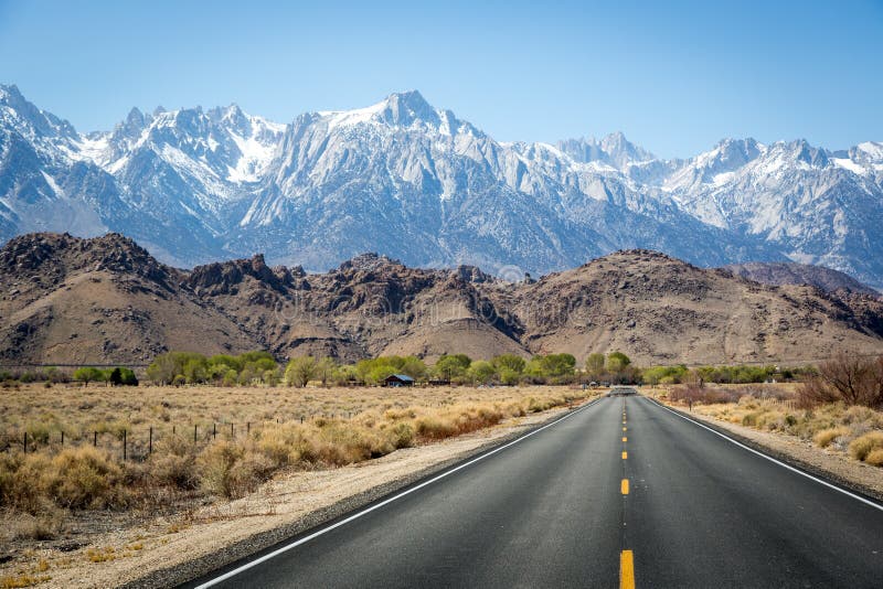 Endless road with snowed mountains in the background. California