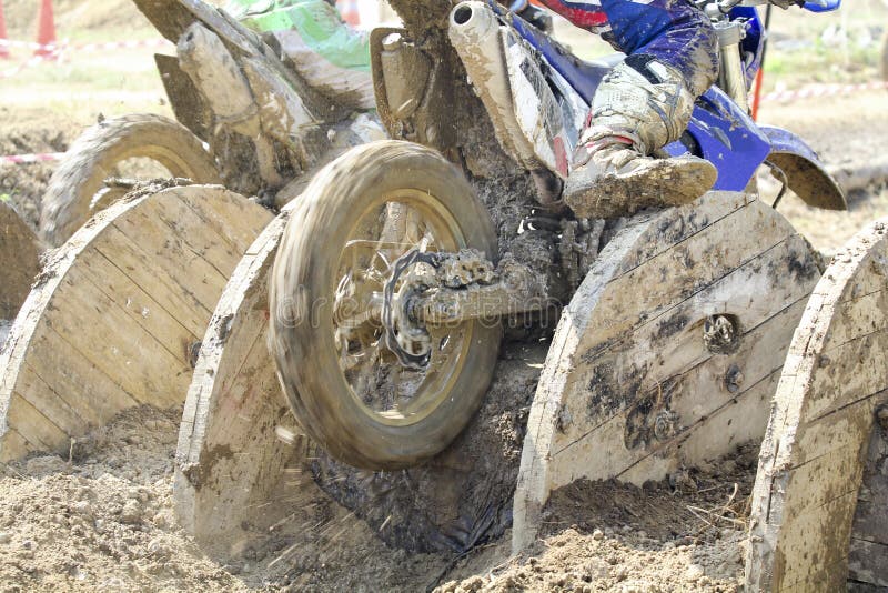 Enduro bikes pass obstacle cable drums in track.