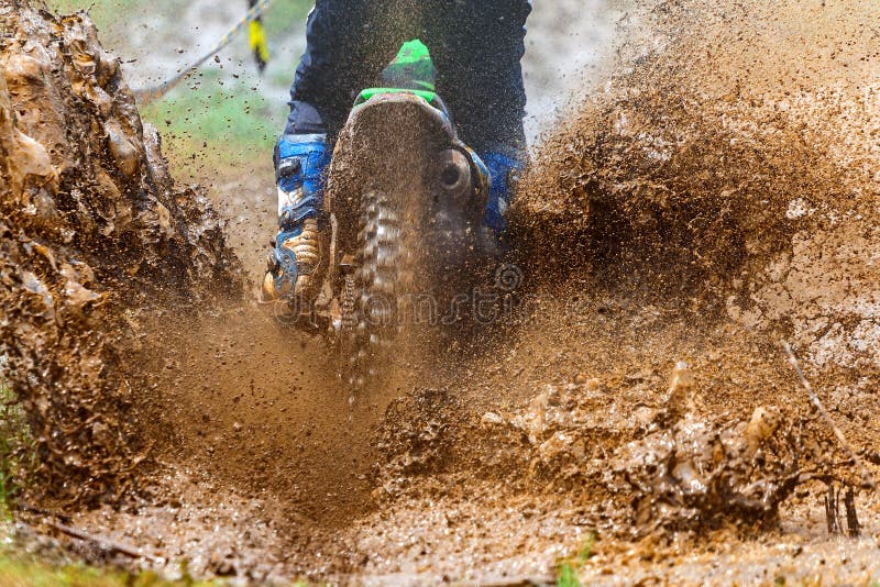 Enduro rides through the mud with big splash.