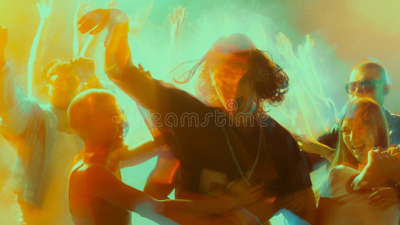 Energetic crowd dancing at a vibrant, colorful party with dynamic lighting. stock image