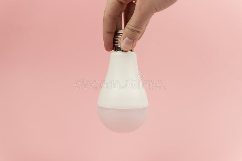Energy saving LED Light bulb in wonam& x27;s hand on pink bacground close up. Concept of saving energy stock photography Energy saving LED Light bulb in wonam& x27;s hand on pink bacground close up. Concept of saving energy stock photography