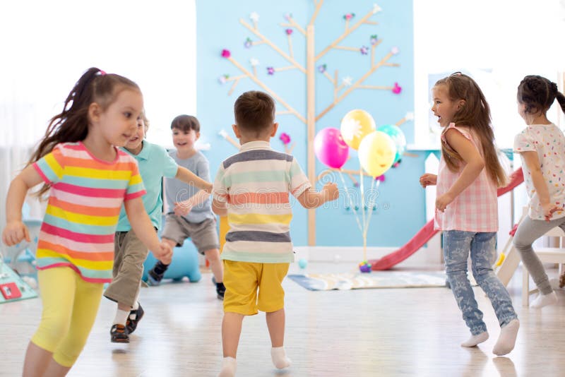 Enfance, loisirs et concept de personnes - groupe d'enfants heureux jouant le jeu et le fonctionnement d'?tiquette dans la chambr images libres de droits Enfance, loisirs et concept de personnes - groupe d'enfants heureux jouant le jeu et le fonctionnement d'?tiquette dans la chambr images libres de droits