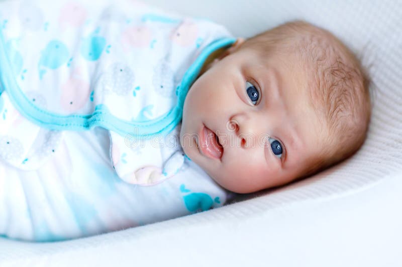 Cute adorable newborn baby wrapped in colorful blanket, looking at the camera. Closeup of peaceful child, little baby girl after sleeping. Family, Birth, new life. Swaddling as method for calm child. Cute adorable newborn baby wrapped in colorful blanket, looking at the camera. Closeup of peaceful child, little baby girl after sleeping. Family, Birth, new life. Swaddling as method for calm child