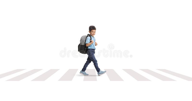 Enfant avec un sac à dos marchant à un passage piéton en zèbre et souriant à la caméra image stock
