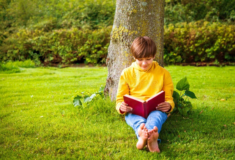 Enfant caucasien look décontracté en jean bleu et sweat à capuche jaune heureux de lire des histoires amusantes dans le grand livr photographie stock libre de droits