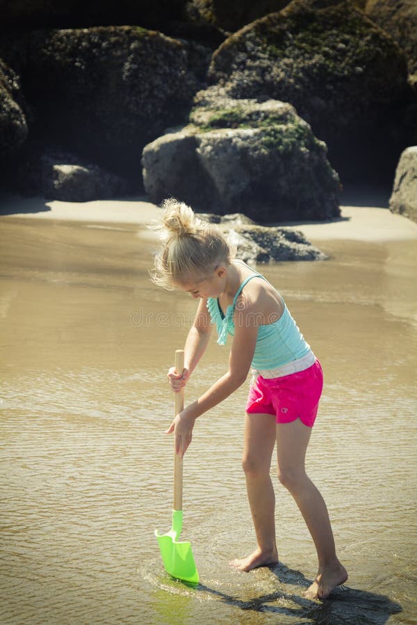 Enfant creusant dans le sable avec une pelle photos stock Enfant creusant dans le sable avec une pelle photos stock
