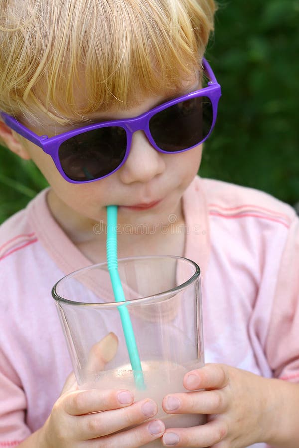 Enfant dans des lunettes de soleil buvant du lait chocolaté photo libre de droits Enfant dans des lunettes de soleil buvant du lait chocolaté photo libre de droits