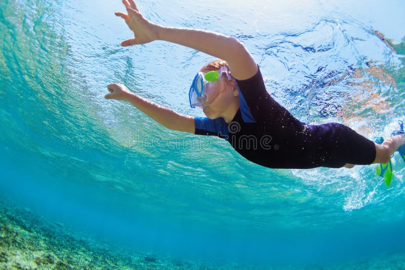 Enfant dans l'eau du fond naviguante au schnorchel de piqué de masque dans la lagune bleue de mer photo stock Enfant dans l'eau du fond naviguante au schnorchel de piqué de masque dans la lagune bleue de mer photo stock