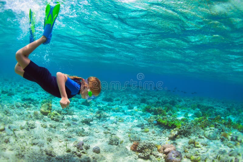 Enfant dans l'eau du fond naviguante au schnorchel de piqué de masque dans la lagune bleue de mer