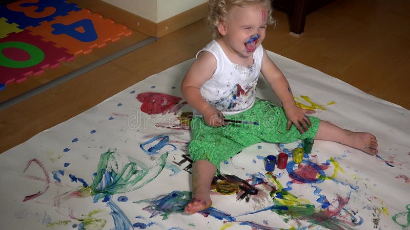 Enfant drôle d'enfant en bas âge avec la peinture colorée de visage sur ses vêtements banque de vidéos