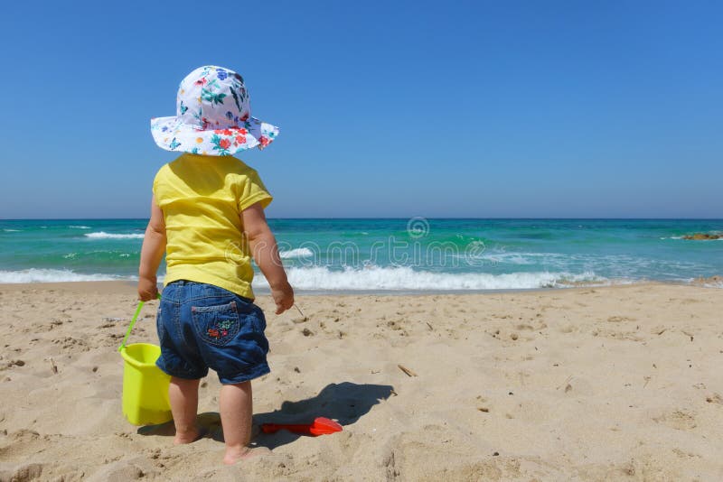Enfant en bas âge de bébé avec le seau et la pelle sur la plage photo stock Enfant en bas âge de bébé avec le seau et la pelle sur la plage photo stock