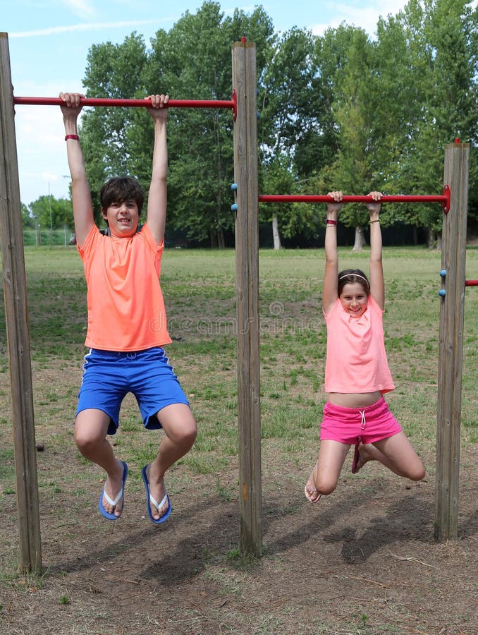 Enfant et petite fille pendant des poteaux pour faire la gymnastique image stock Enfant et petite fille pendant des poteaux pour faire la gymnastique image stock