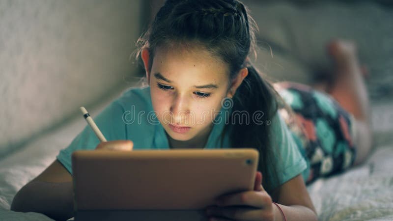 Enfant fille tenant une tablette numérique. apprentissage des adolescents à la maison. enfant écrire des devoirs pour la fille de clips vidéos