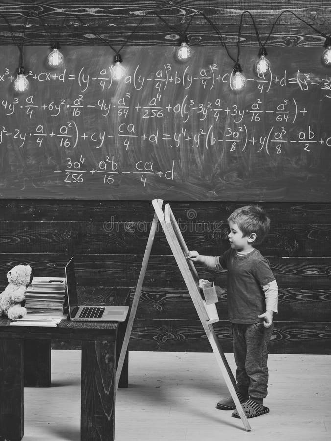 Enfant heureux ayant l'amusement Écriture de Little Boy sur le tableau Enfant de vue de côté devant le conseil vert avec l'équati photos stock Enfant heureux ayant l'amusement Écriture de Little Boy sur le tableau Enfant de vue de côté devant le conseil vert avec l'équati photos stock