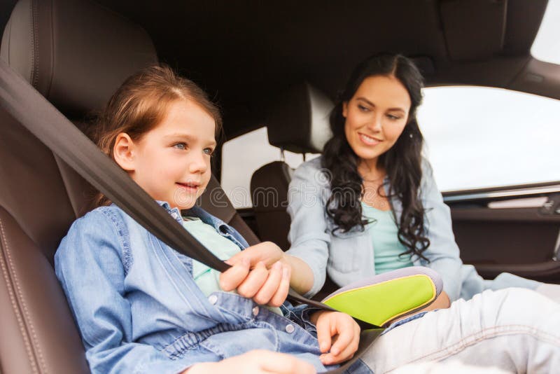 Enfant heureux d'attache de femme avec la ceinture de sécurité dans la voiture