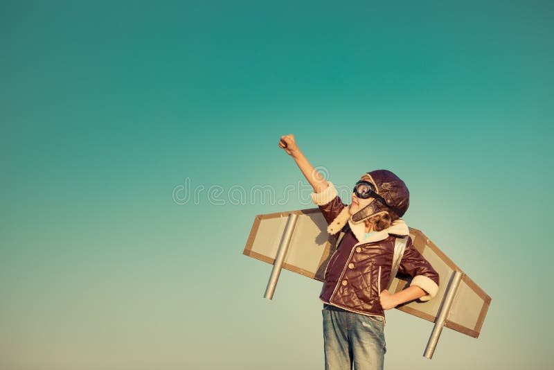 Kid pilot with toy jet pack against autumn sky background. Happy child playing outdoors. Kid pilot with toy jet pack against autumn sky background. Happy child playing outdoors