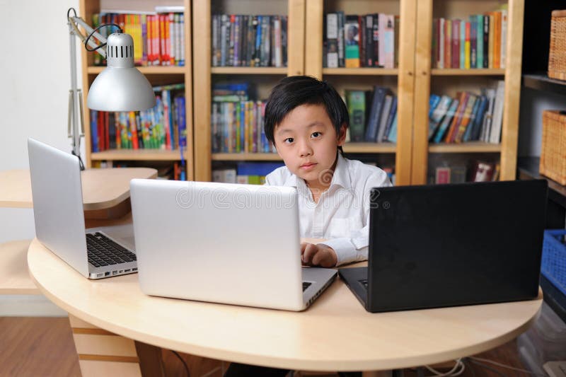 Enfant intelligent travaillant sur les ordinateurs multiples