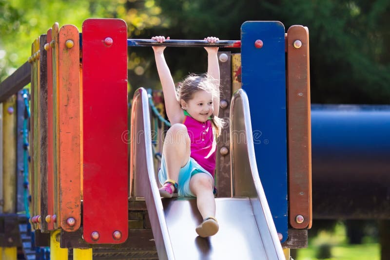 Enfant jouant sur le terrain de jeu extérieur en été photo stock Enfant jouant sur le terrain de jeu extérieur en été photo stock