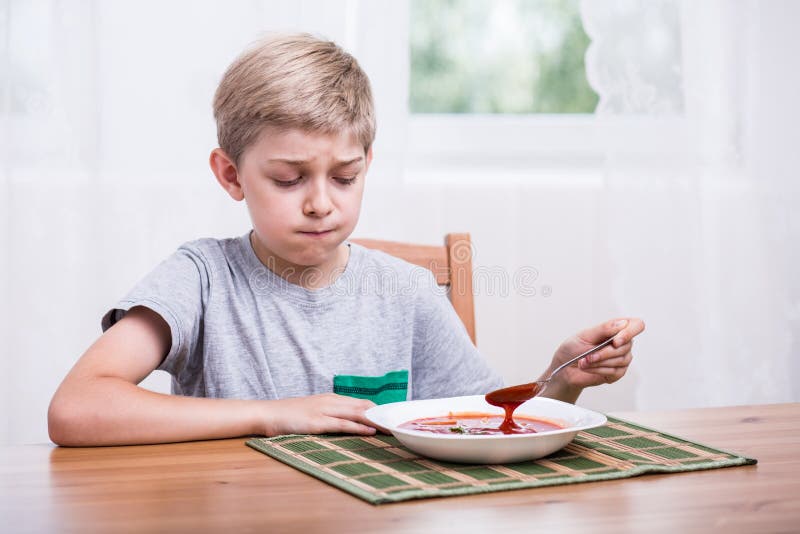 Enfant mangeant de la soupe avec dégoût image libre de droits