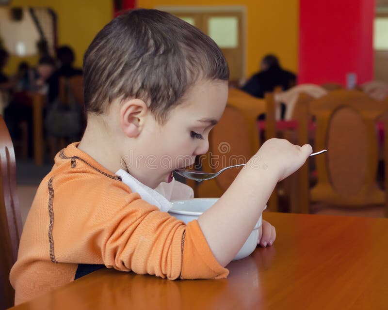 Enfant mangeant de la soupe dans le restaurant image libre de droits Enfant mangeant de la soupe dans le restaurant image libre de droits