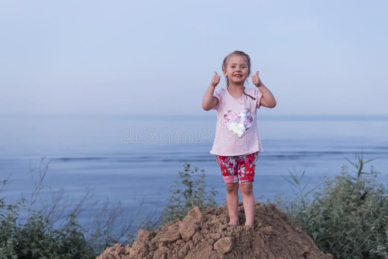 Enfant montrant des pouces à la mer photographie stock libre de droits Enfant montrant des pouces à la mer photographie stock libre de droits