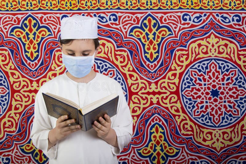 Enfant musulman tenant une lanterne ramadane et un masque médical devant le fond du ramadan image stock