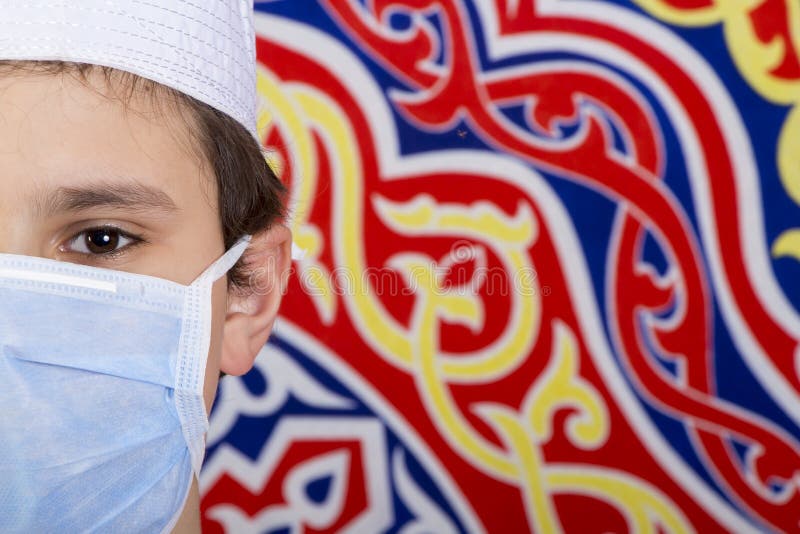 Enfant musulman tenant une lanterne ramadane et un masque médical devant le fond du ramadan photos libres de droits