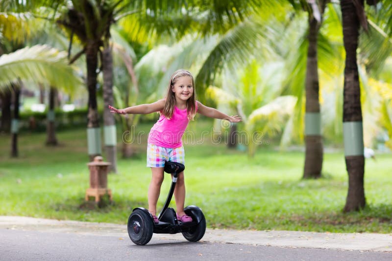 Enfant sur le conseil de vol plané Enfants conduisant le scooter photos stock Enfant sur le conseil de vol plané Enfants conduisant le scooter photos stock