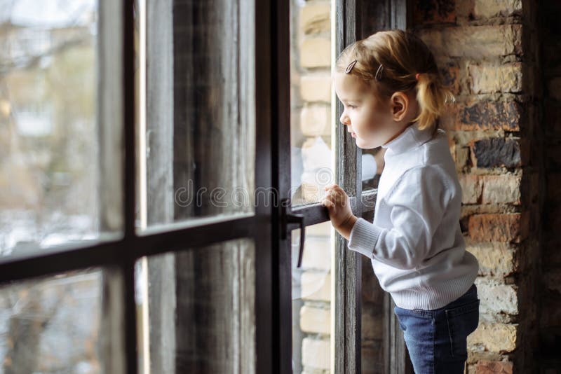 Enfant triste regardant la fenêtre photo stock Enfant triste regardant la fenêtre photo stock