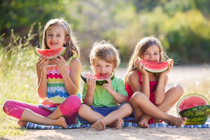 Enfant trois de sourire heureux mangeant la pastèque photo stock