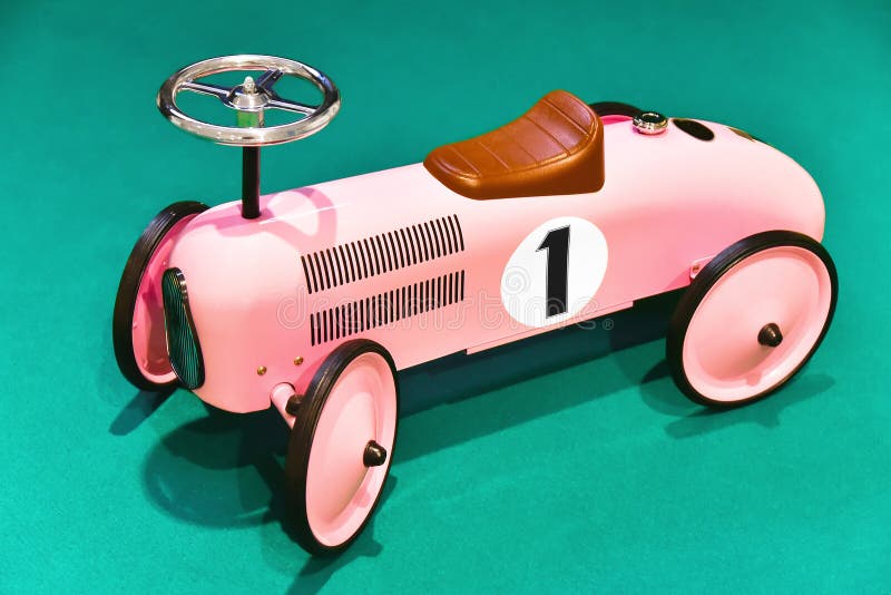 Children's toy pink retro car with number one on an aquamarine green background. Children's toy pink retro car with number one on an aquamarine green background