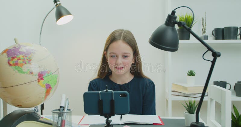 Enfant enfant école fille élever la main distance cours d'apprentissage en utilisant l'application mobile regarder en ligne cours. Enfant enfant école fille élever la main distance cours d'apprentissage en utilisant l'application mobile regarder le tutorat en ligne leçon vidéo appel dans l'application virtuel étudier à la maison dans la salle de classe