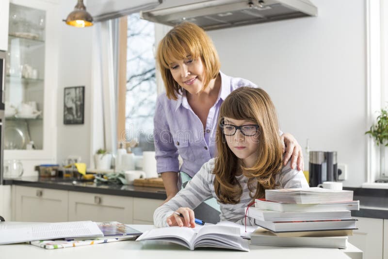 Enfantez aider la fille en faisant le travail dans la cuisine photo stock