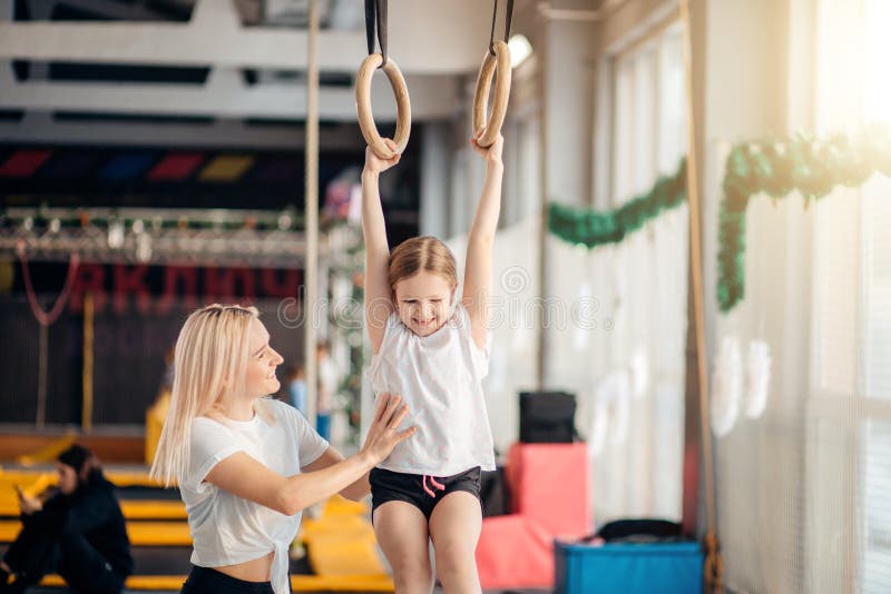 Enfantez la fille de aide pour jouer des sports sur les anneaux gymnastiques photos libres de droits Enfantez la fille de aide pour jouer des sports sur les anneaux gymnastiques photos libres de droits