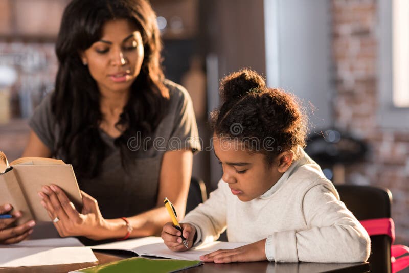 Enfantez regarder la petite fille mignonne faisant le travail à la maison image libre de droits Enfantez regarder la petite fille mignonne faisant le travail à la maison image libre de droits