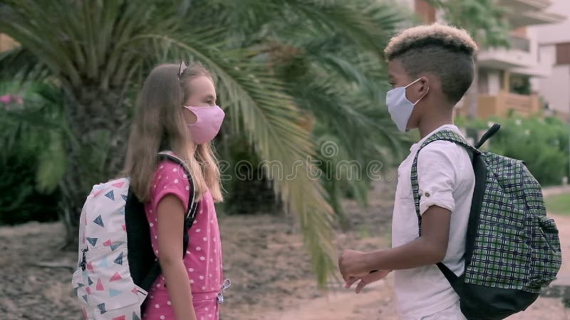 Enfants adorables d'âge scolaire de l'ethniques multiples petits parlant même si à l'école à pied ensemble. Enfants avec des sacs clips vidéos