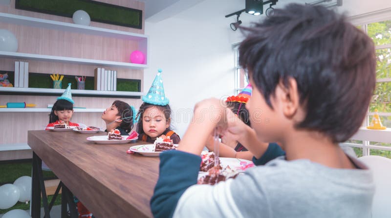 Enfants asiatiques heureux mangeant son gâteau d'anniversaire en partie image stock Enfants asiatiques heureux mangeant son gâteau d'anniversaire en partie image stock