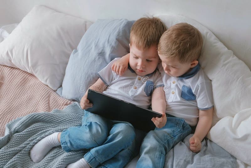 Enfants avec la tablette Deux enfants en bas âge de jumeaux de garçons regardant la bande dessinée le comprimé se trouvant sur le photos libres de droits Enfants avec la tablette Deux enfants en bas âge de jumeaux de garçons regardant la bande dessinée le comprimé se trouvant sur le photos libres de droits