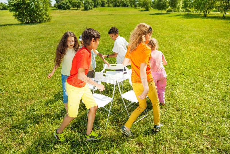 Enfants courus autour de jouer le jeu de chaises musicales